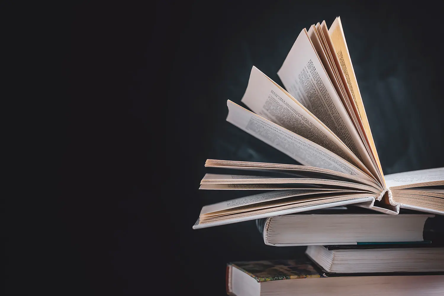 Open book on stacked closed books.