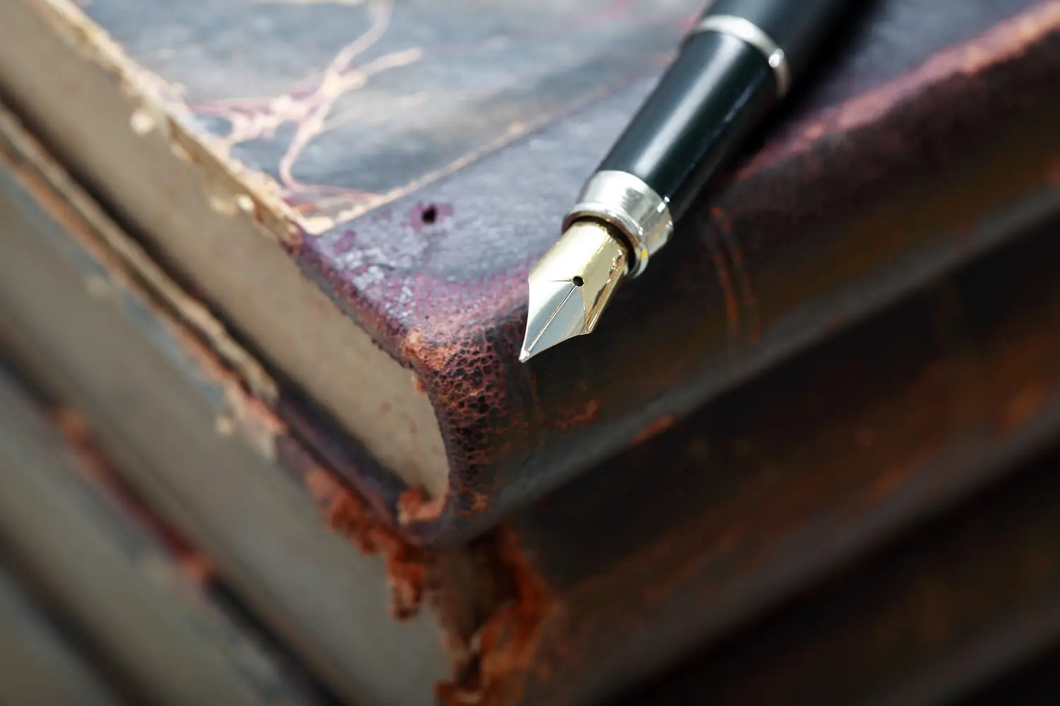 Fountain pen on stack of old books.